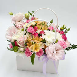 Pastel flower arrangement in a white handled box with a lavender ribbon