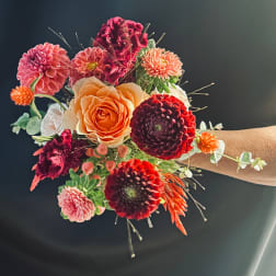 Colorful wrist corsage with roses and pom-pom flowers on a wrist