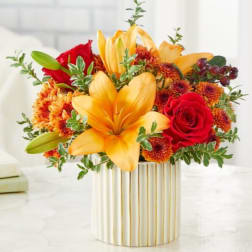 Yellow lilies and red roses in a striped gold vase
