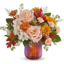 Peach roses and orange daisies in a striped glass vase