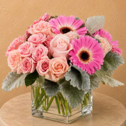 Pink roses and gerbera daisies in a clear square vase