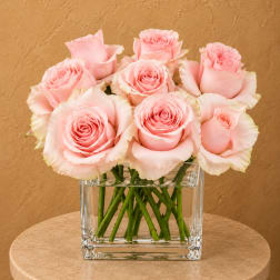 Pink roses arranged in a clear square glass vase