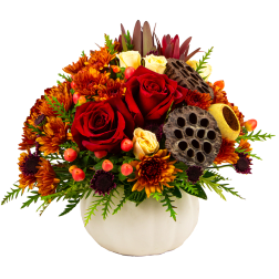 Red and cream roses in a white vase with orange chrysanthemums and lotus pods