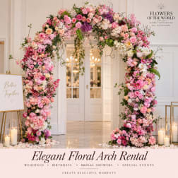 Pink and white floral arch framing a doorway with candles nearby