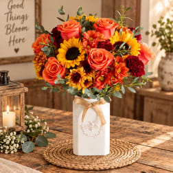 Bouquet of orange roses and sunflowers in a white vase