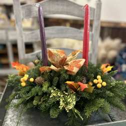 Evergreen centerpiece with fall ribbon, berries, and two taper candles on a metal tray