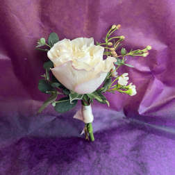 Cream rose boutonniere with small white buds and ribbon on a purple background