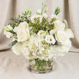 White roses and carnations arranged in a clear glass vase