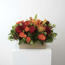 Orange and red floral arrangement in a wooden box
