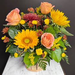 Peach roses and yellow sunflowers in a wooden basket arrangement