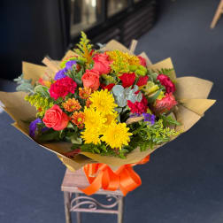Mixed bouquet of roses, chrysanthemums, and carnations wrapped in kraft paper