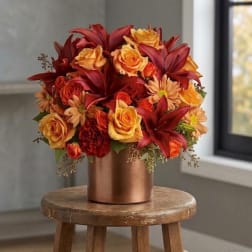Red and orange floral arrangement in a copper vase