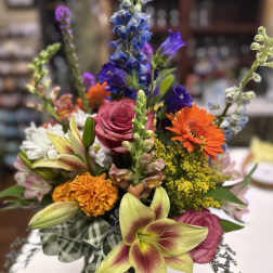 Mixed bouquet with pink roses, orange gerberas, and lilies in a plaid wrap