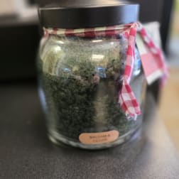 Glass jar candle with a black lid and plaid ribbon