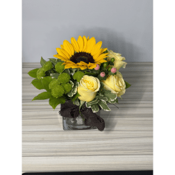 Sunflower and yellow rose arrangement in a square glass vase