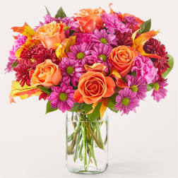 Bouquet of orange roses and pink daisies in a clear glass vase