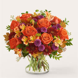 Orange roses and purple mums in a clear glass vase