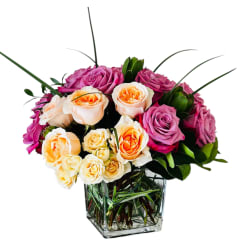 Bouquet of pink and peach roses in a clear square vase