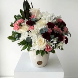 Mixed bouquet of white, pink, and burgundy flowers in a white vase