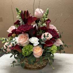 Basket arrangement of pink and burgundy flowers with eucalyptus