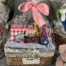 Gift basket with toiletries and greeting cards wrapped in clear plastic and a pink bow