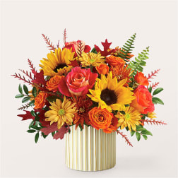 Autumn bouquet of sunflowers, roses, and mums in a striped vase