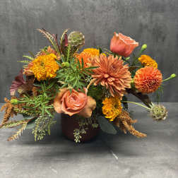Orange and peach mixed bouquet in a dark vase