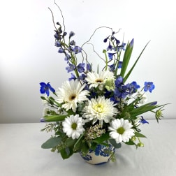 Blue and white mixed flower arrangement in a patterned vase