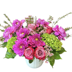 Pink and magenta flowers arranged in a ribbed white vase