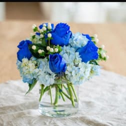 Blue roses and pale hydrangeas in a clear glass vase