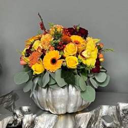 Yellow and burgundy floral arrangement in a silver pumpkin container