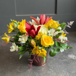 Yellow roses and lilies arranged in a copper vase