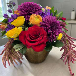 Mixed bouquet of roses and purple blooms in a gold vase