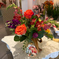 Orange roses and mixed flowers arranged in a glass vase