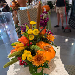 Autumn floral arrangement with orange blooms and a pumpkin accent