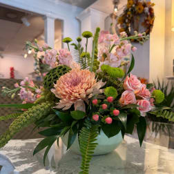 Pink and peach floral arrangement in a pale green vase