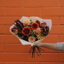 Handheld bouquet of peach roses and orange gerbera daisies