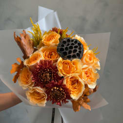 Bouquet of orange roses and burgundy mums with dried leaves