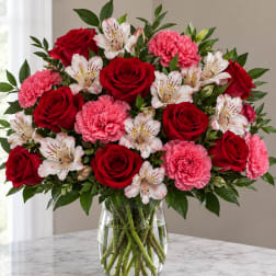 Bouquet of red roses, pink carnations, and white alstroemeria in a glass vase