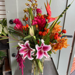 Tropical bouquet with pink lilies and orange flowers in a glass vase