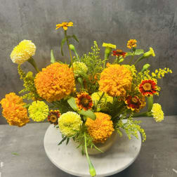 Orange and yellow marigold arrangement in a round vase