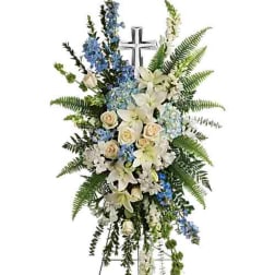Tall white and blue floral standing spray with lilies and roses on a cross easel