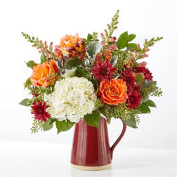 Bouquet of orange, white, and red flowers in a red pitcher vase
