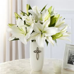 White lilies in a tall vase with a cross emblem