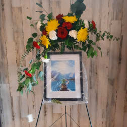 Floral standing spray with red, yellow, and white flowers on an easel