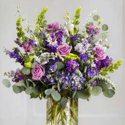 Tall bouquet of purple and pink flowers in a clear glass vase