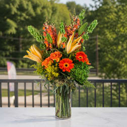 Tall orange and yellow floral arrangement in a clear glass vase