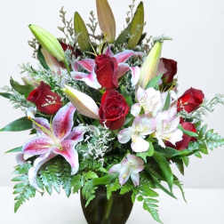 Bouquet of red roses and pink lilies in a dark glass vase