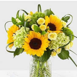 Sunflower bouquet with pale yellow roses in a clear glass vase