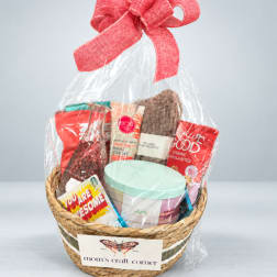 Gift basket with snacks and a mint-lidded container wrapped in clear plastic and a red bow